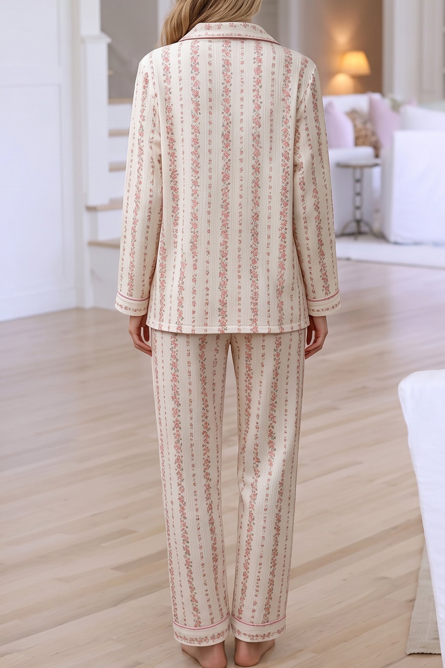 Back view of woman in cream pajamas with pink floral stripes.