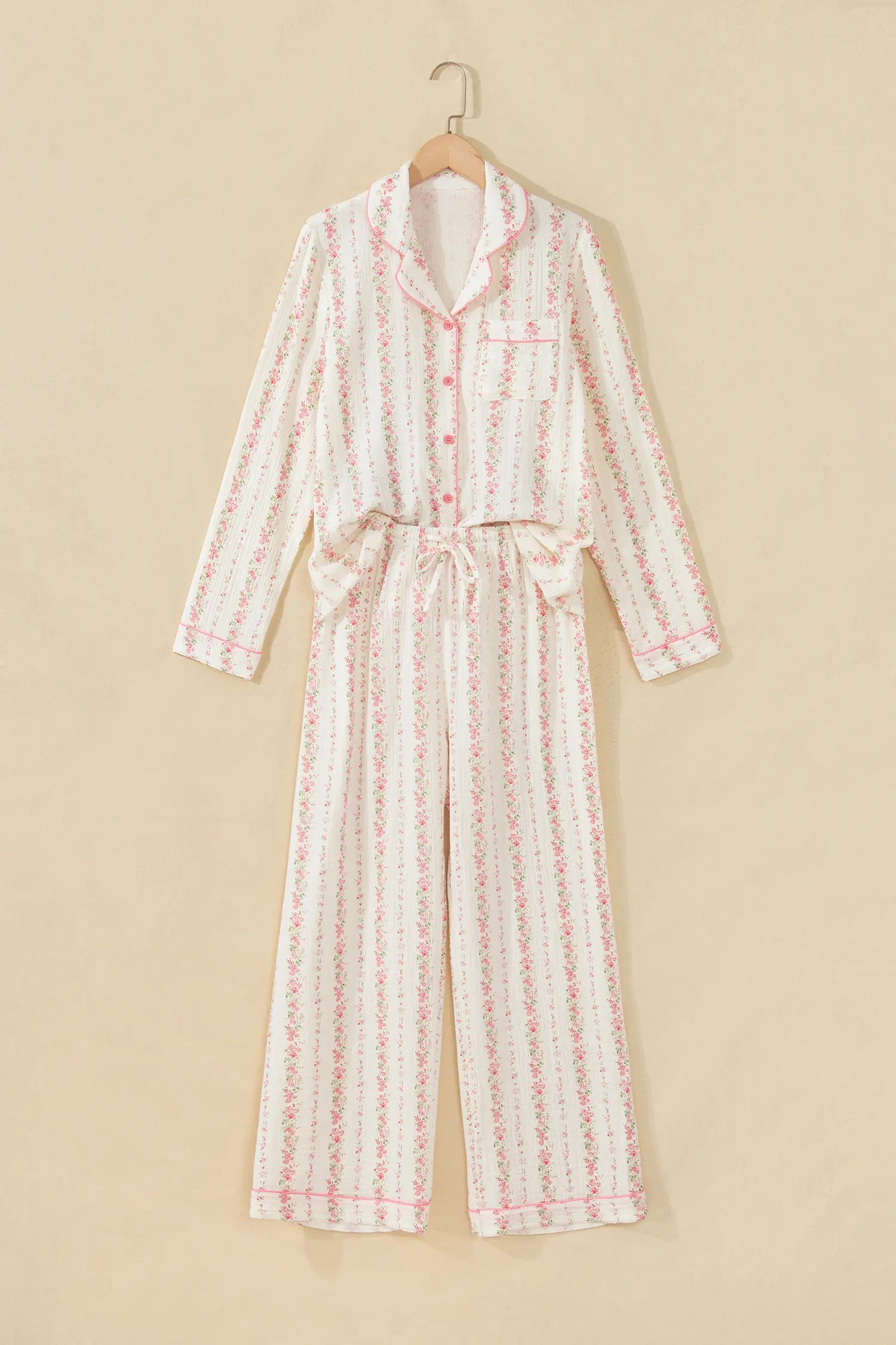 White long-sleeve pajamas with pink floral print on wooden hanger.