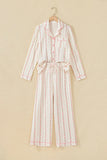 White long-sleeve pajamas with pink floral print on wooden hanger.