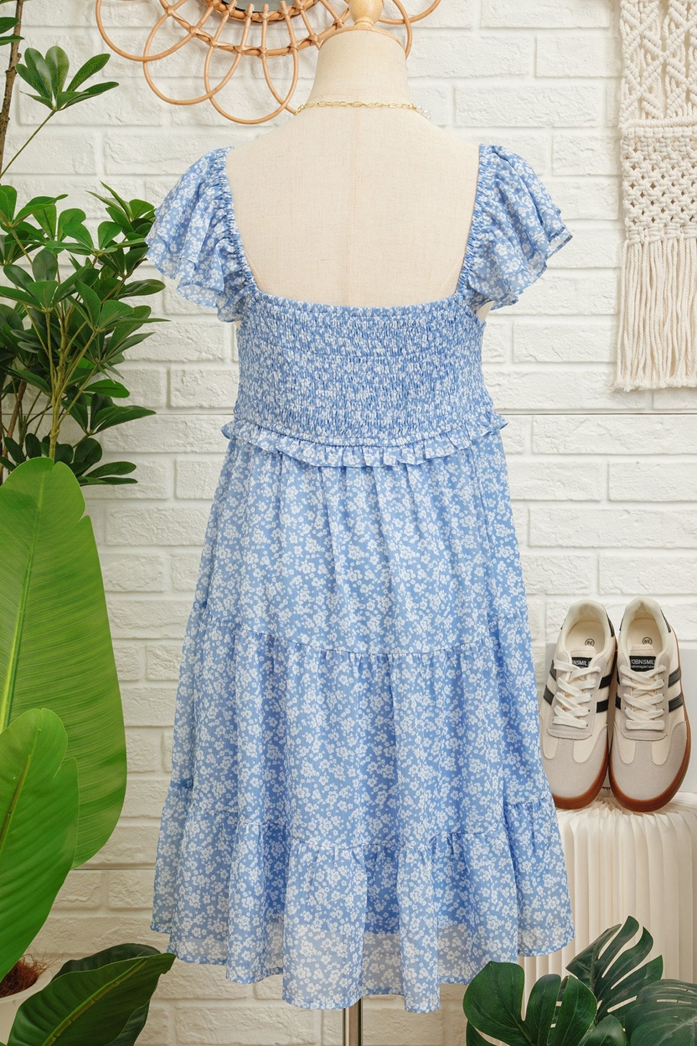 Blue floral dress on a mannequin with sneakers and plants in the background