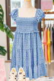 Blue floral dress on a mannequin with sneakers in front, in a store setting.