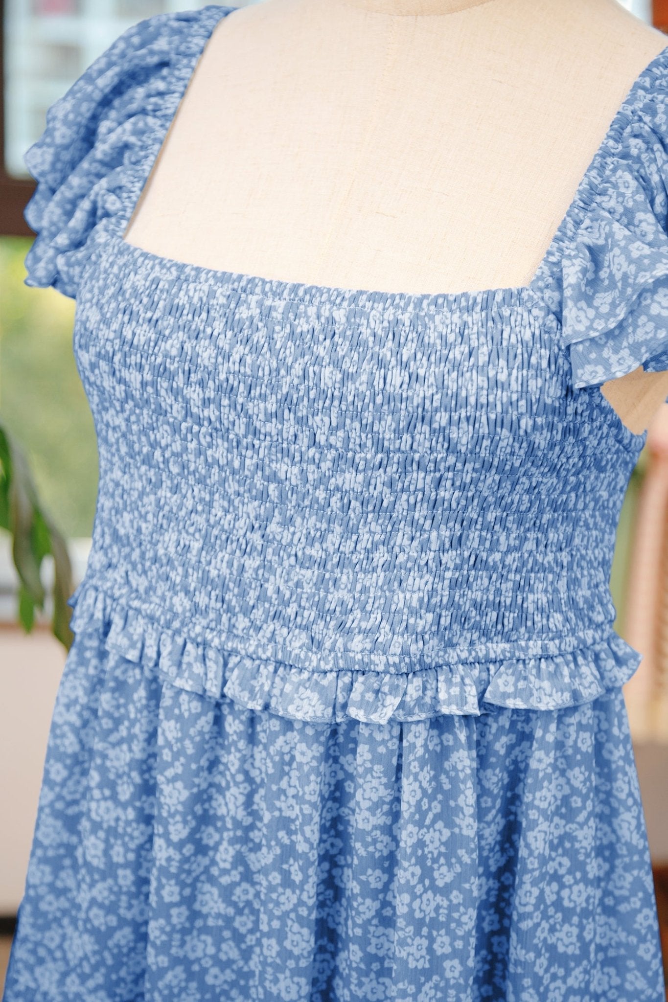 Blue floral dress with ruffled details on a blurred background