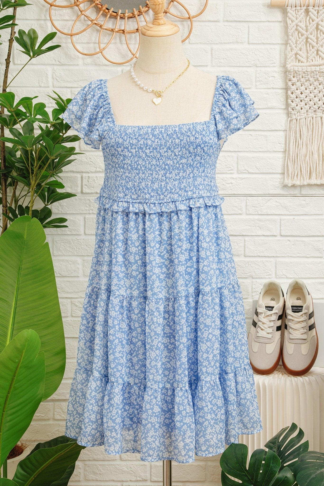Blue floral dress on a mannequin with sneakers and plants in the background