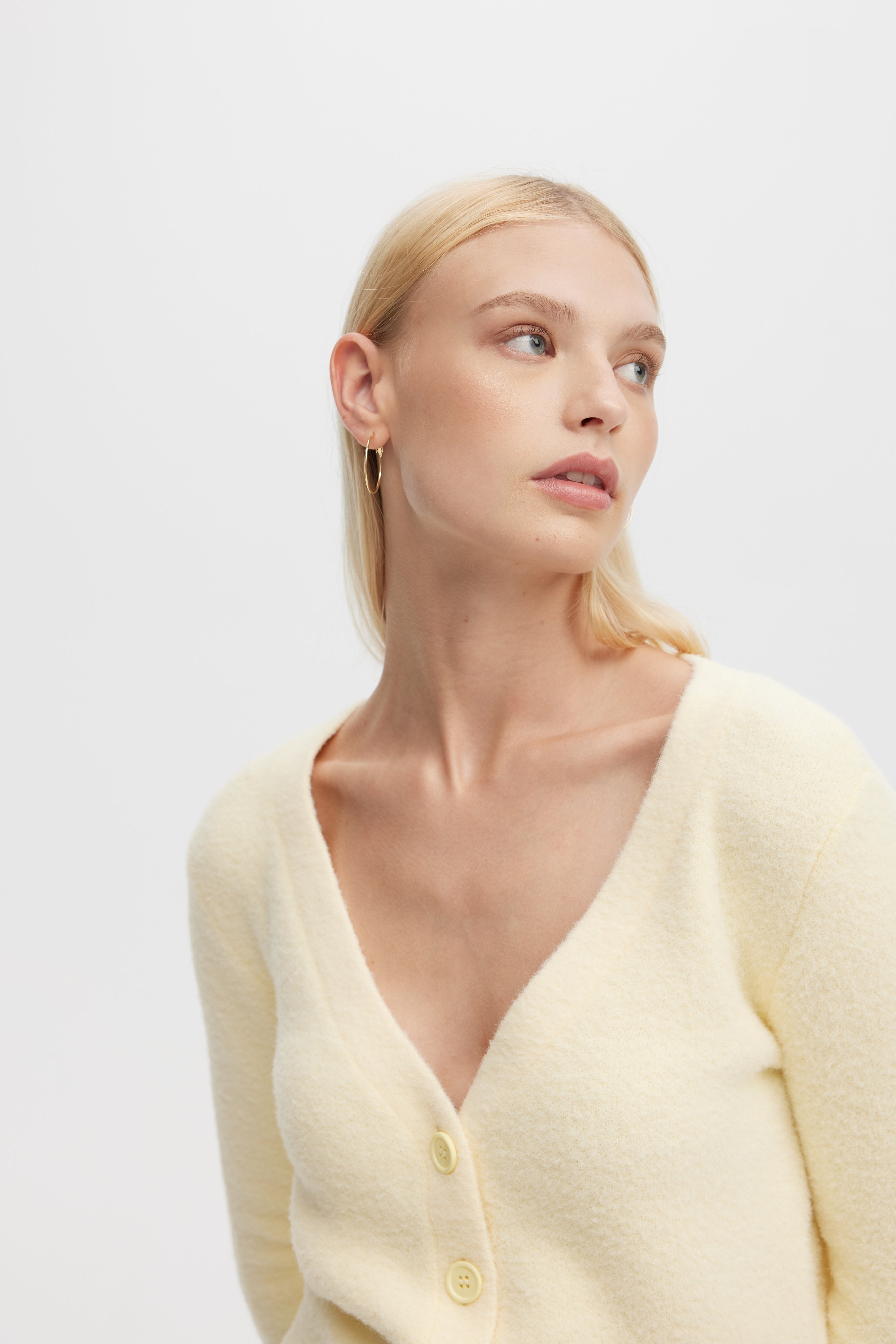 Woman wearing a light yellow cardigan against a white background