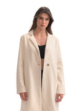 Woman wearing a long beige coat on a white background