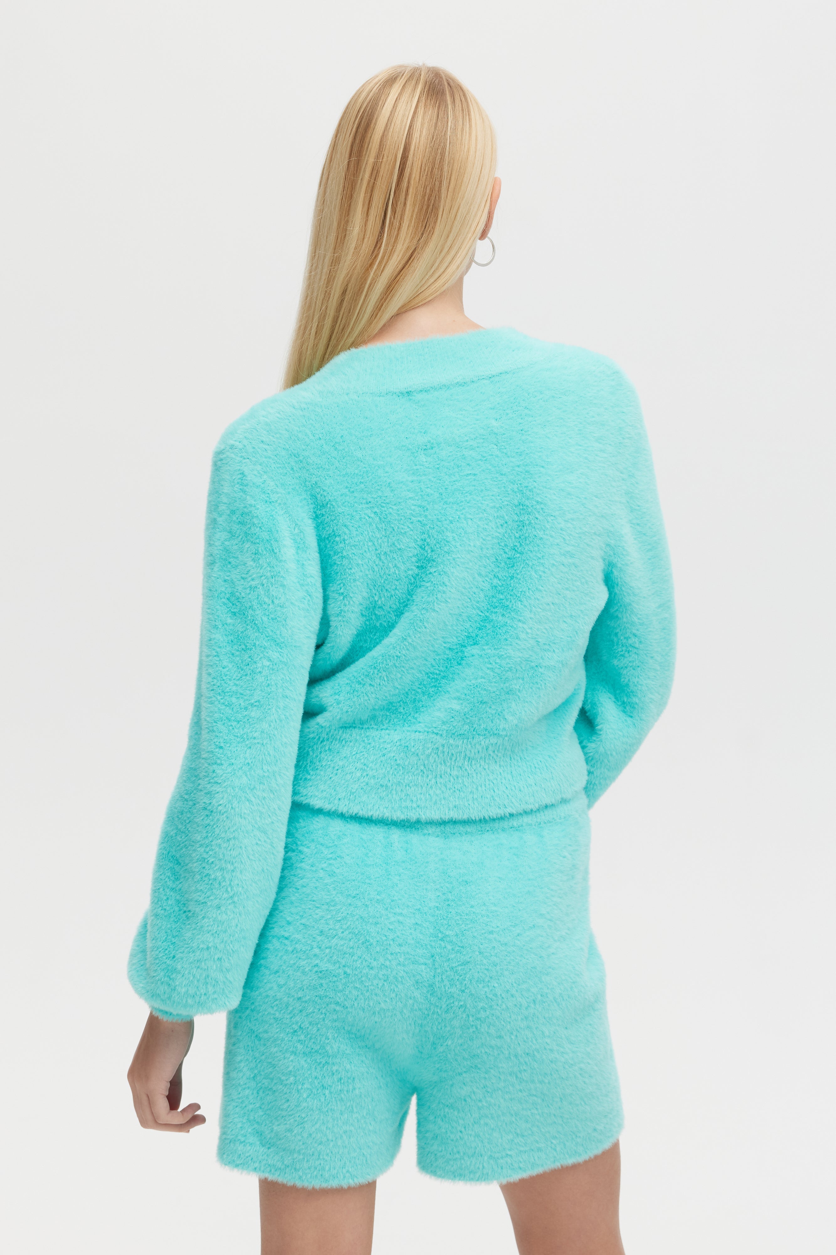 Person wearing a teal outfit on a plain background