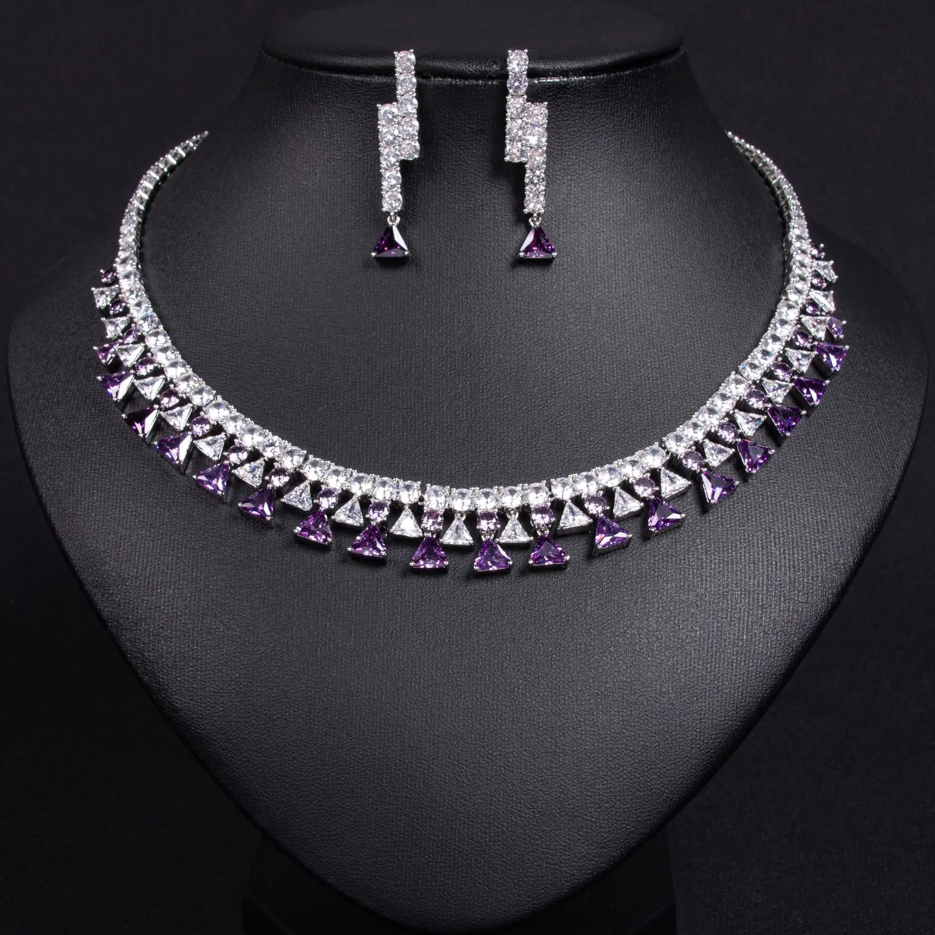 Necklace and earrings set with purple and clear gemstones on a black background