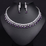 Necklace and earrings set with purple and clear gemstones on a black background