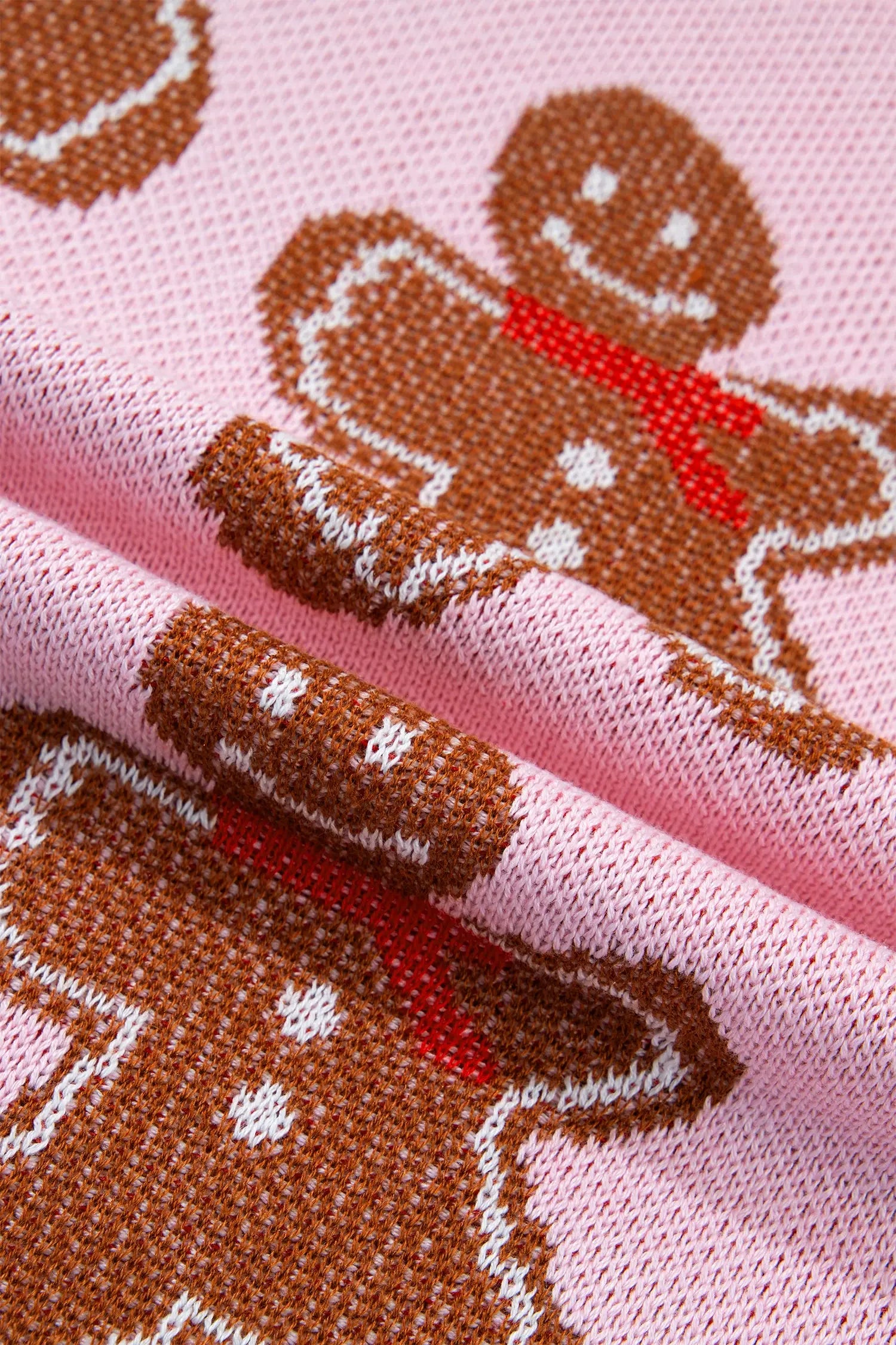Close-up of pink knit fabric with a repeating gingerbread man pattern in brown, white, and red.
