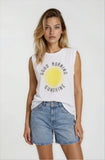 Woman wearing a white sleeveless shirt with 'Good Morning Sunshine' print and denim shorts on a white background