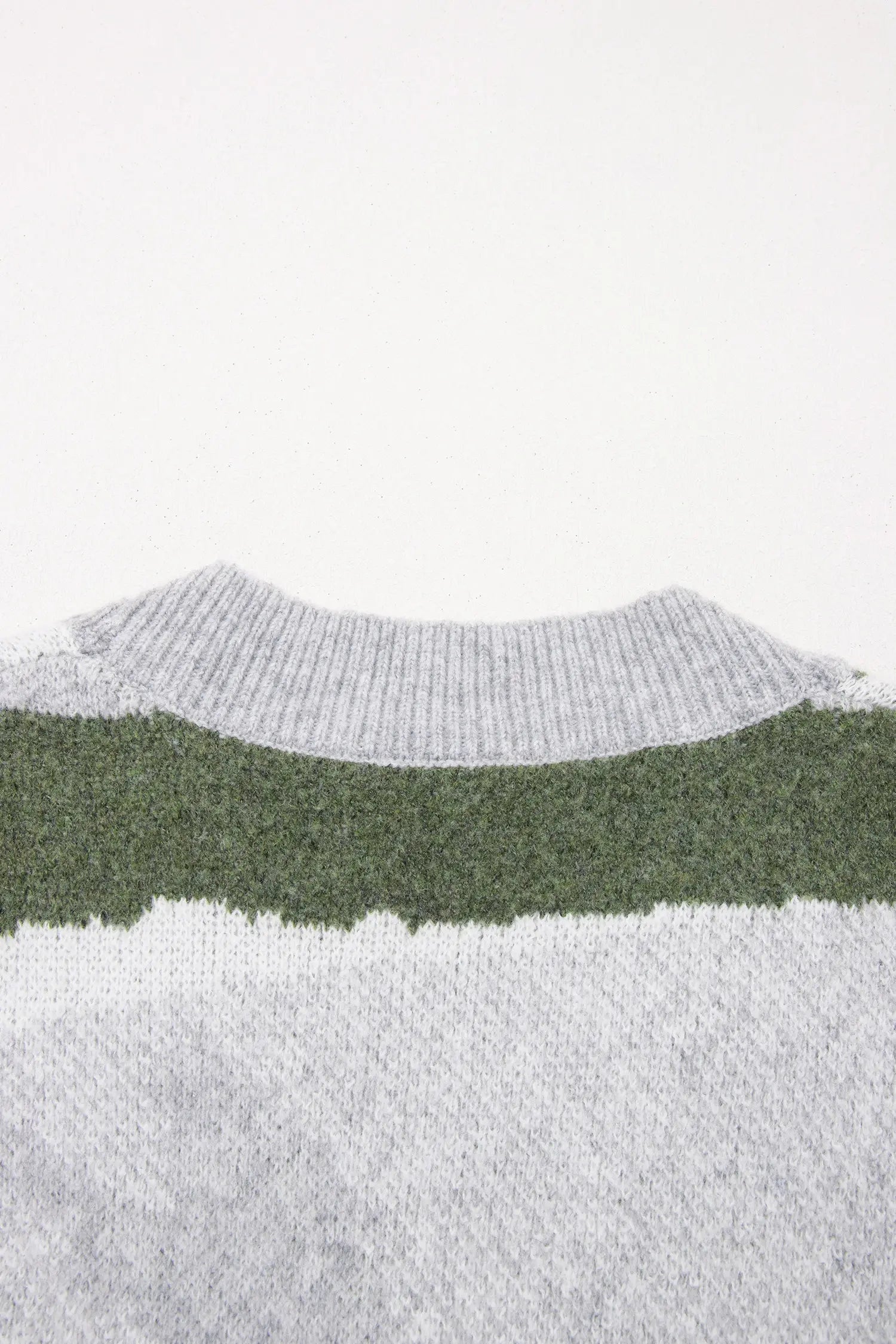 Close-up of a knit sweater showing a wide horizontal band of dark green between two lighter gray sections, photographed against a plain white background.