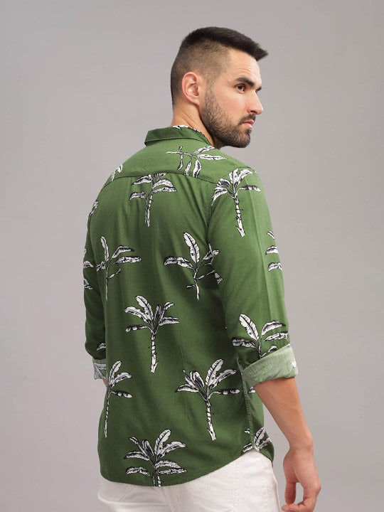 Man wearing a green shirt with palm tree pattern on a gray background