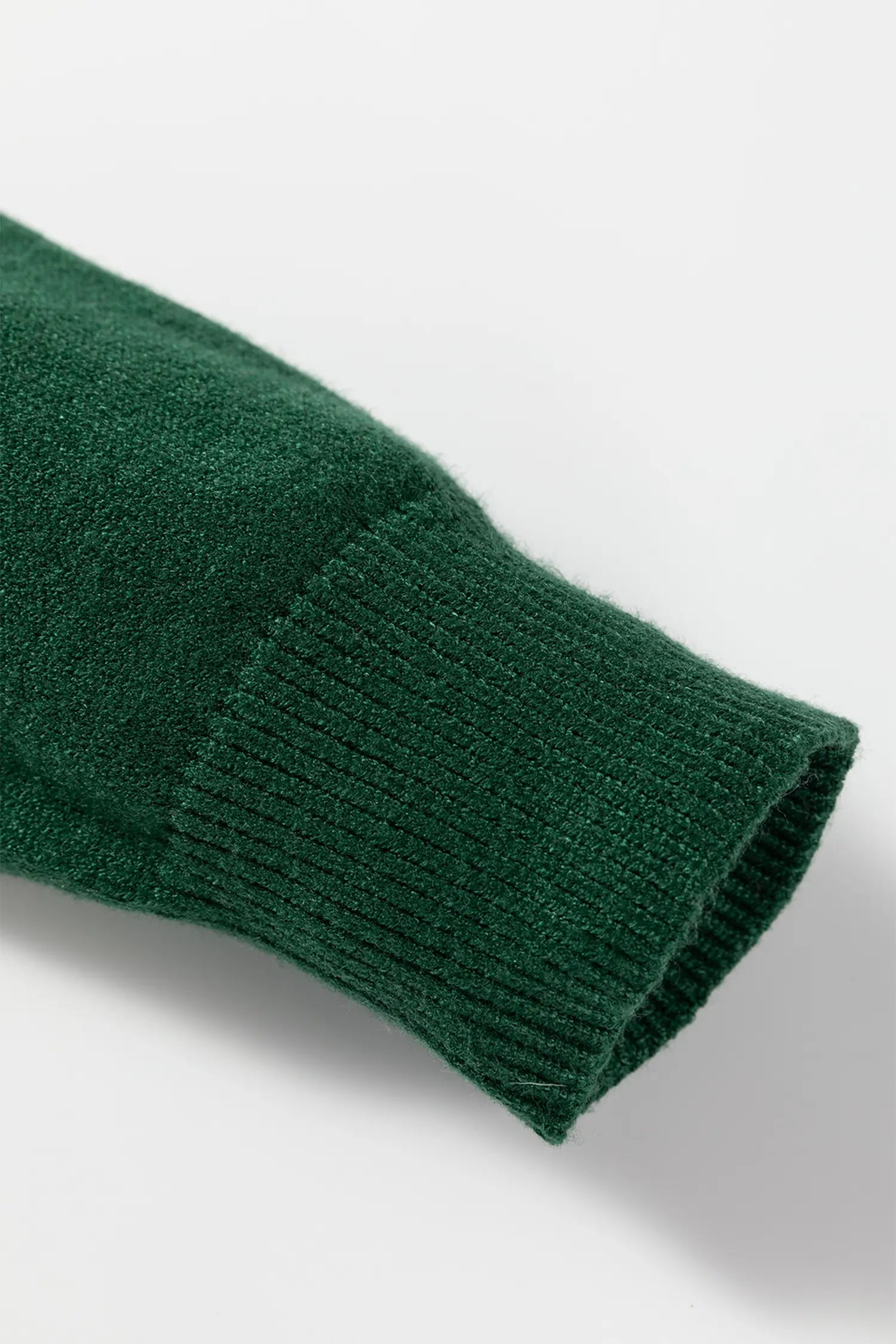 Close-up of a green knitted sleeve on a light gray background