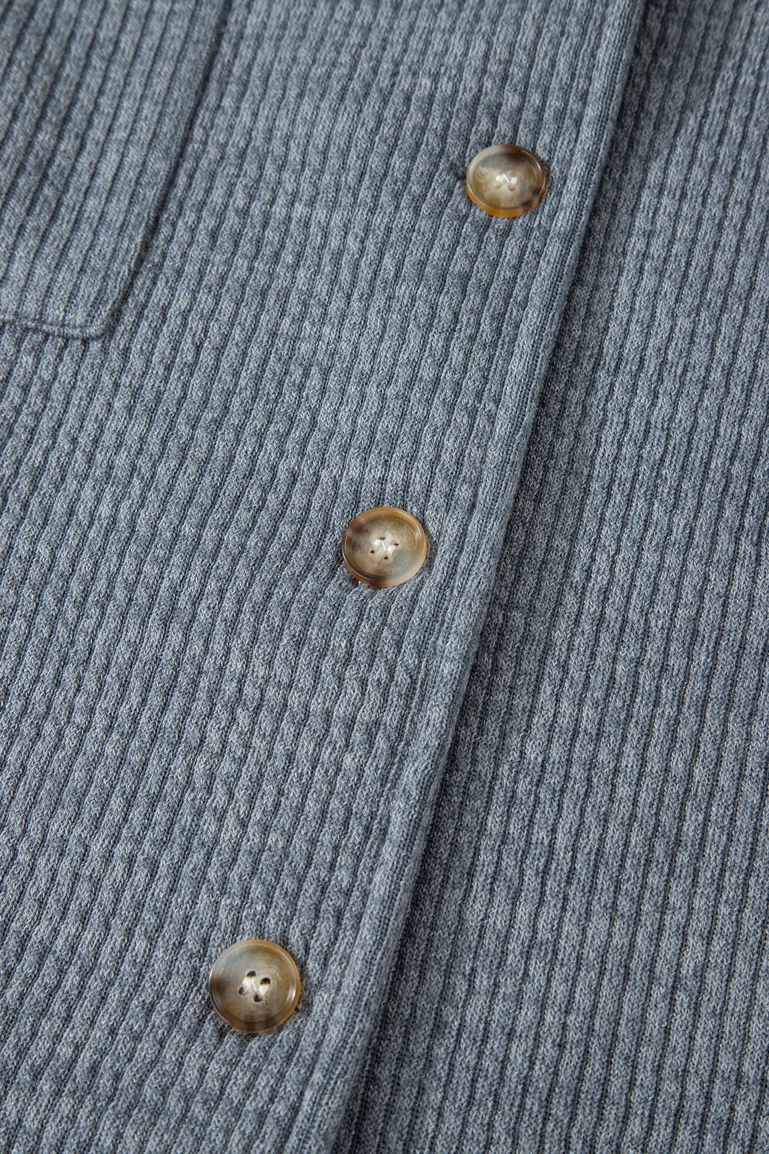 Close-up of a ribbed gray sweater with buttons