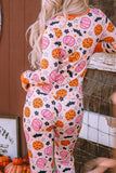 Woman in cream Halloween-print pajamas with pumpkins, bats, stars, and flowers.