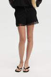 Person wearing black shorts with lace trim on a white background