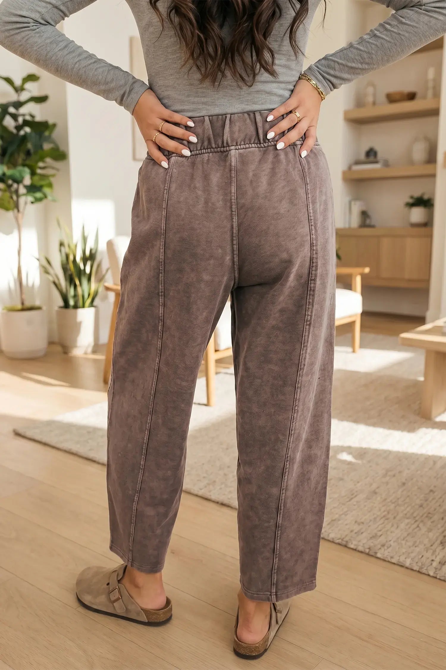 Person wearing brown pants and a gray top in a home setting