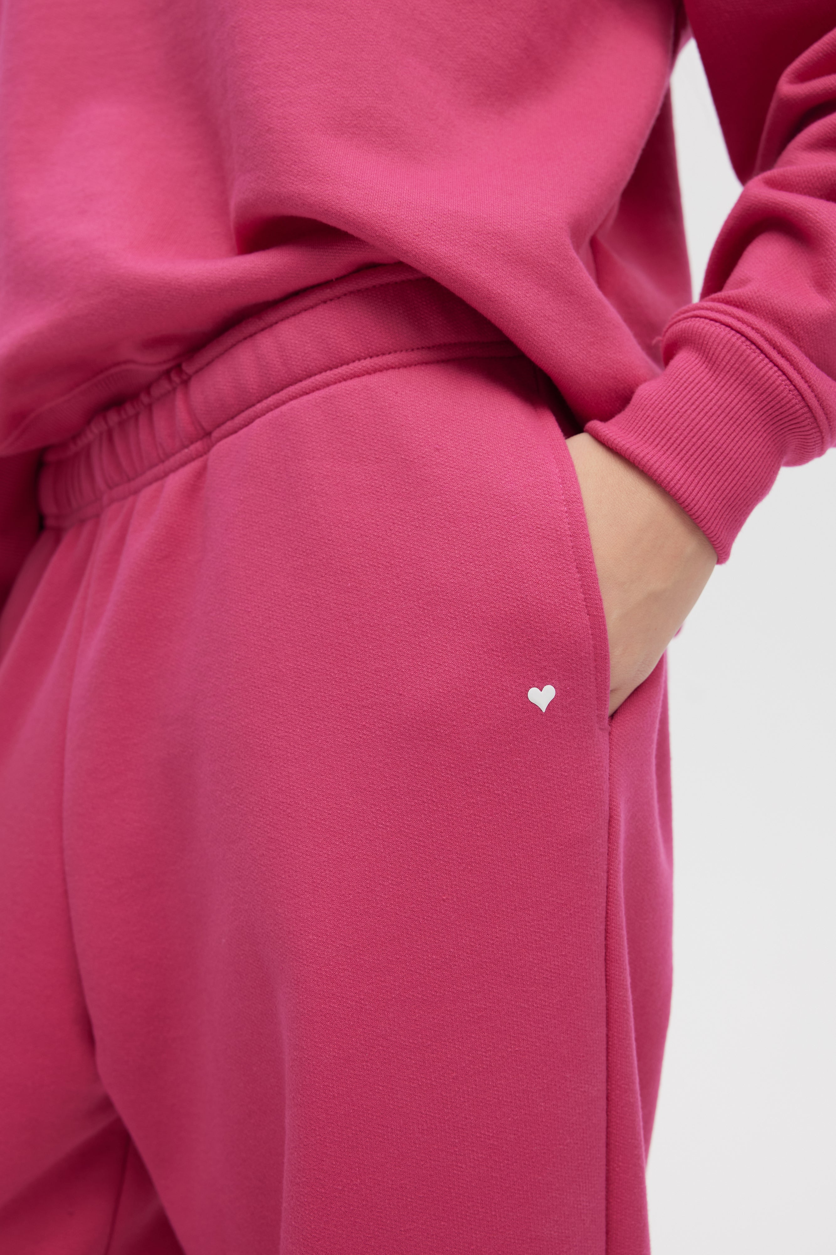 Close-up of a pink tracksuit with a heart detail on a white background