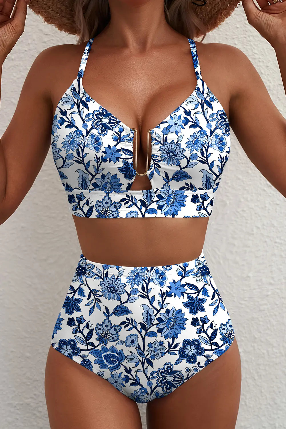 Woman wearing a blue floral two-piece swimsuit against a neutral background