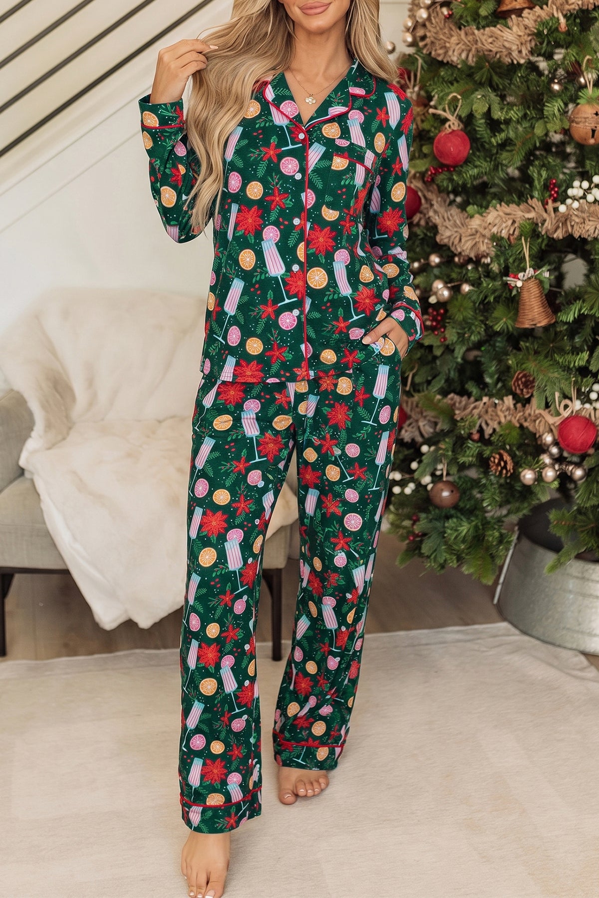 Woman in long-sleeve pajamas with festive Christmas print beside decorated tree
