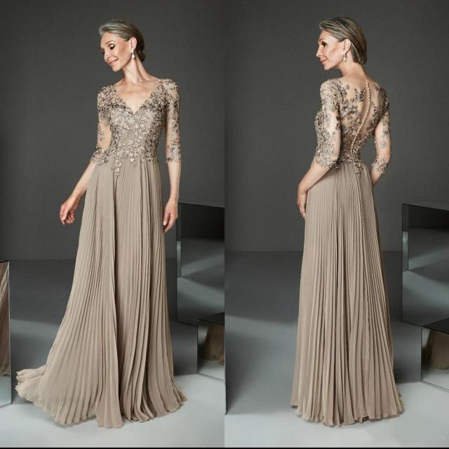 Woman wearing a long, elegant dress with intricate detailing in a studio setting.