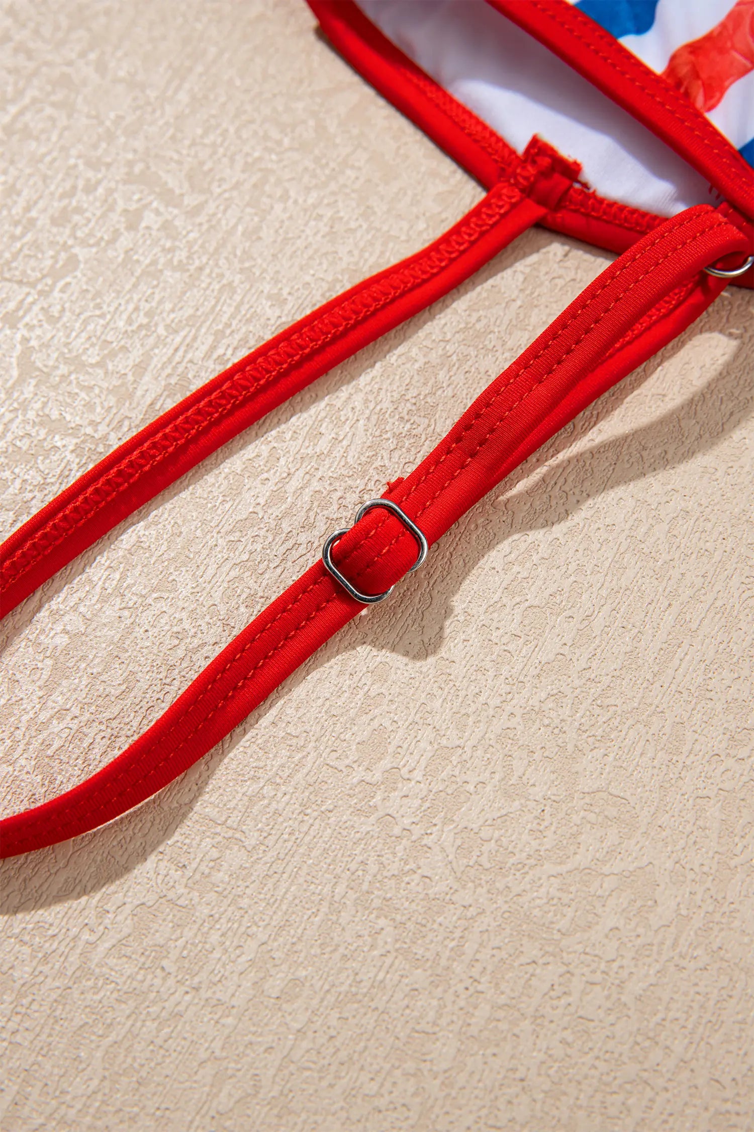 Red strap with a metal buckle on a beige background