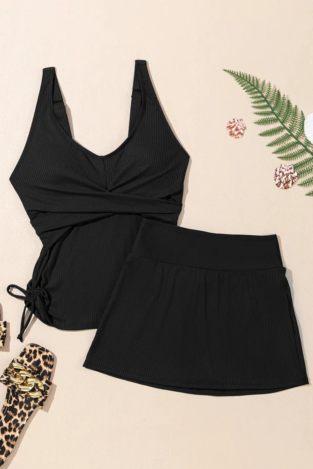 Black swimsuit with a tie front design on a beige background with decorative elements.