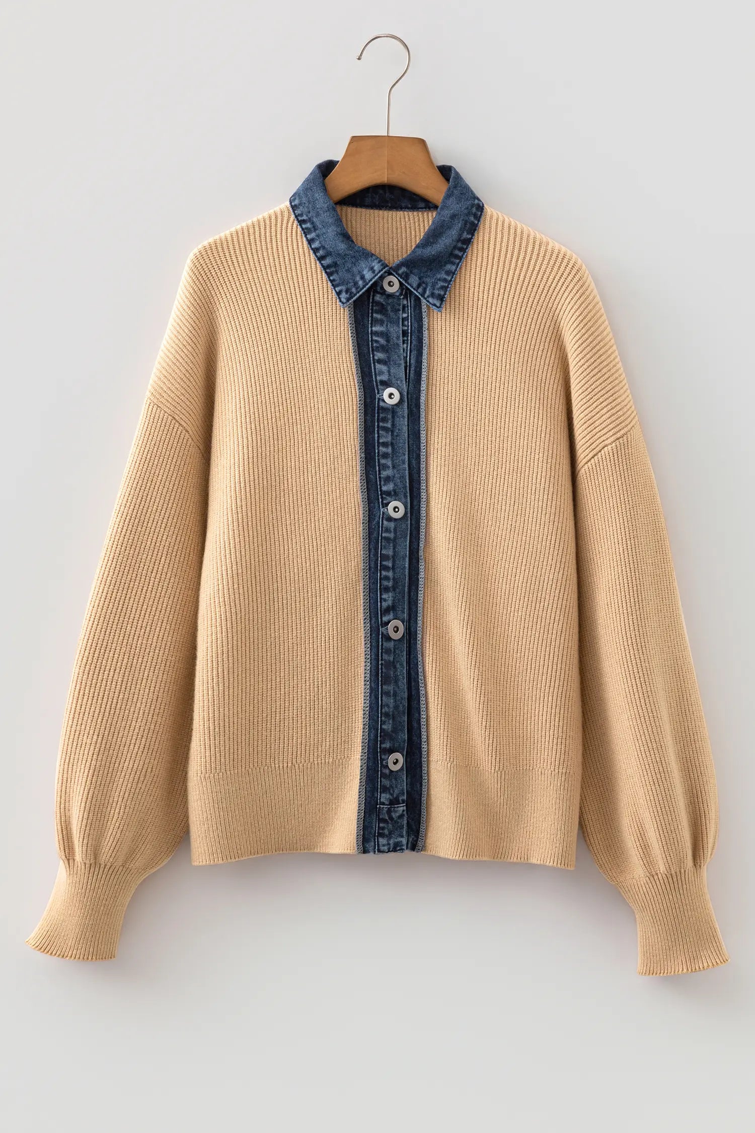 A beige ribbed knit cardigan sweater with a contrasting blue denim collar and front placket, hanging on a wooden hanger against a light gray background.