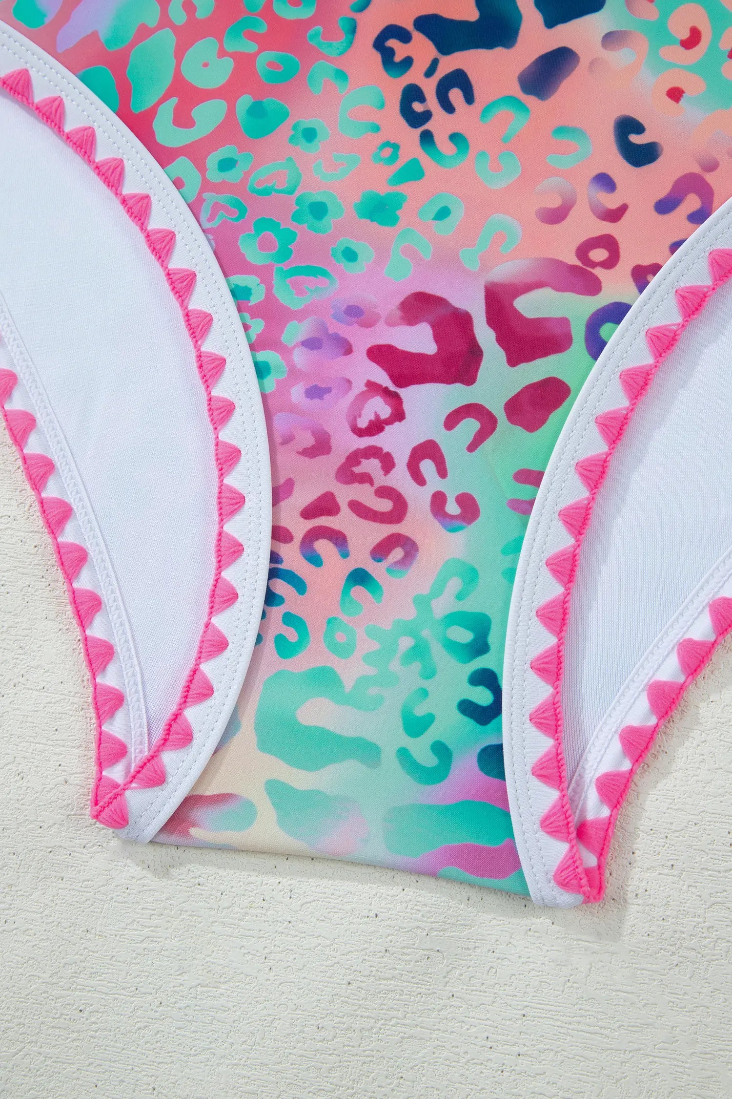 Colorful swimsuit with pink leopard print and white trim on a light background