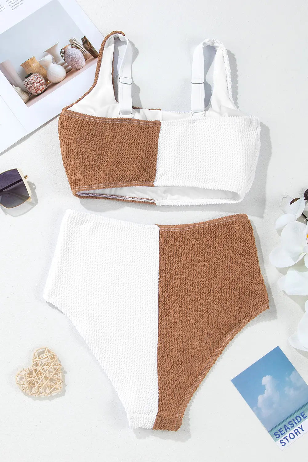 Brown and white bikini set on a light surface with decorative items.