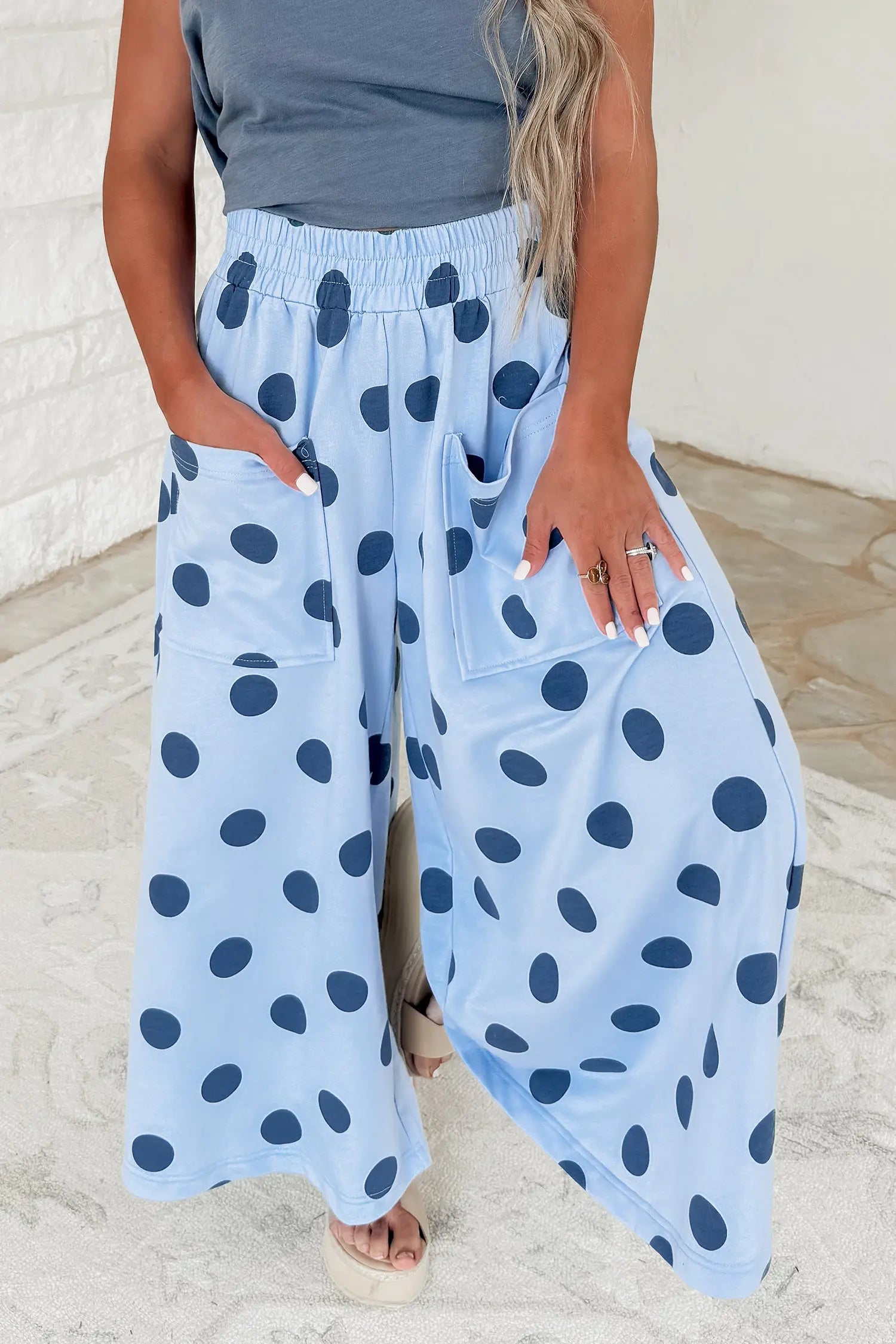 A person wearing light blue wide-leg pants with dark blue polka dots, standing in a light-colored indoor setting.