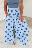 A person wearing light blue wide-leg pants with dark blue polka dots, standing in a light-colored indoor setting.