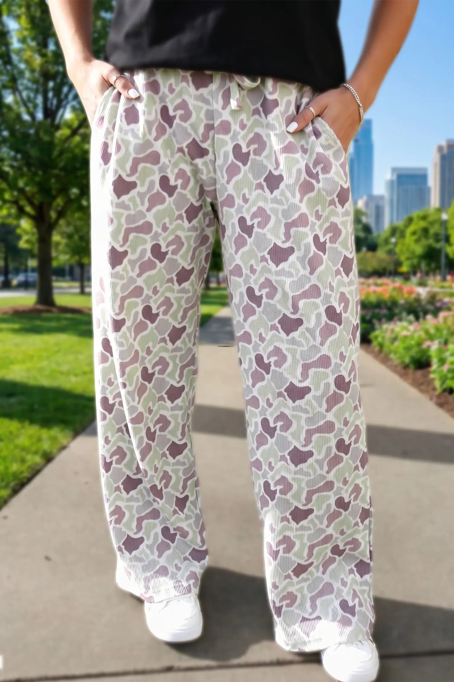 Person wearing patterned pants walking outdoors with a cityscape in the background