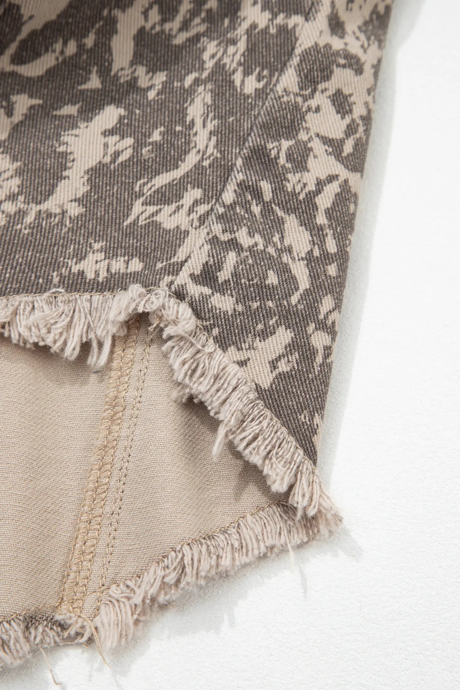 Close-up of frayed cropped textile with mottled taupe-beige exterior and smooth beige lining.