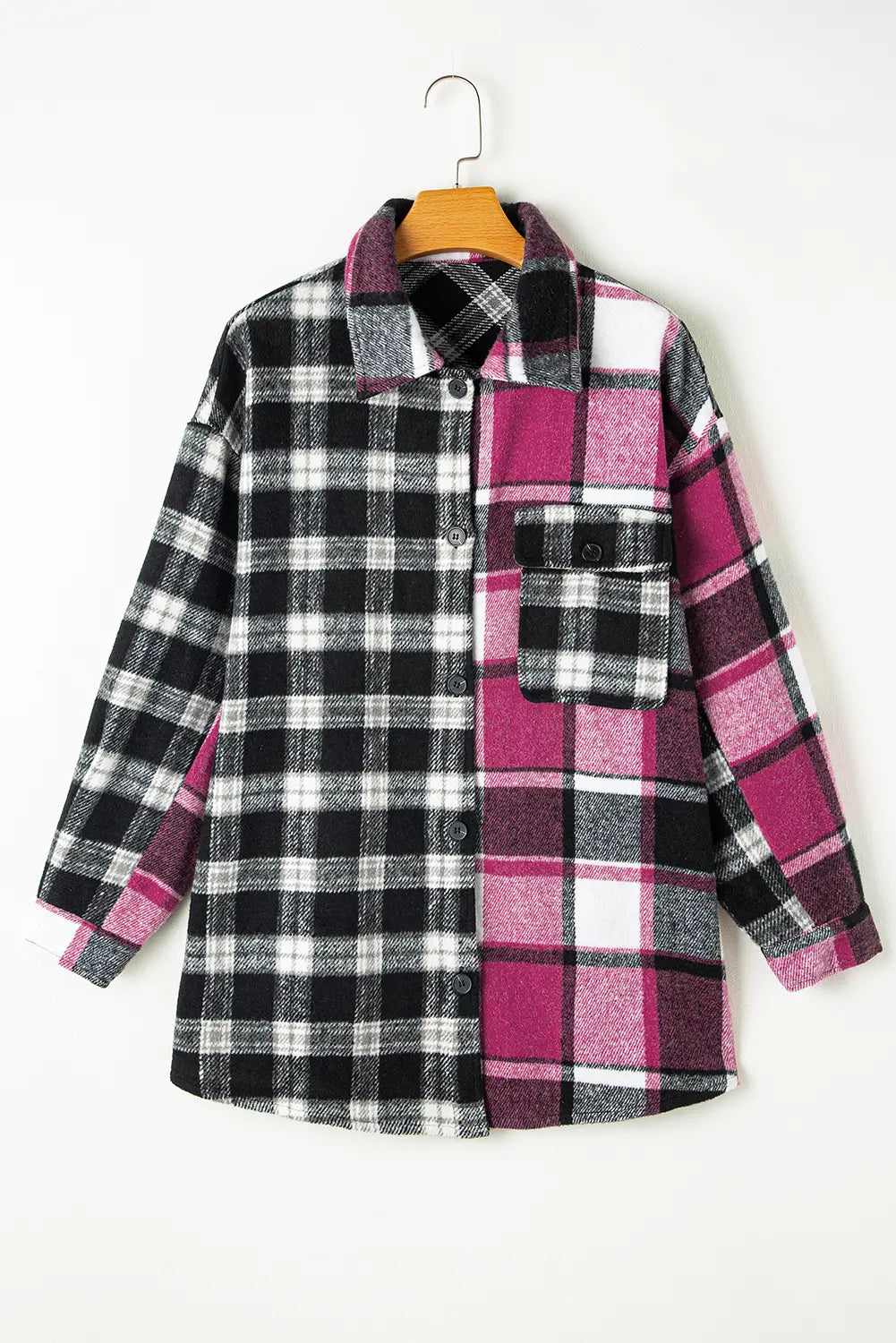 Plaid shirt with black, white, and pink pattern on a hanger against a white background