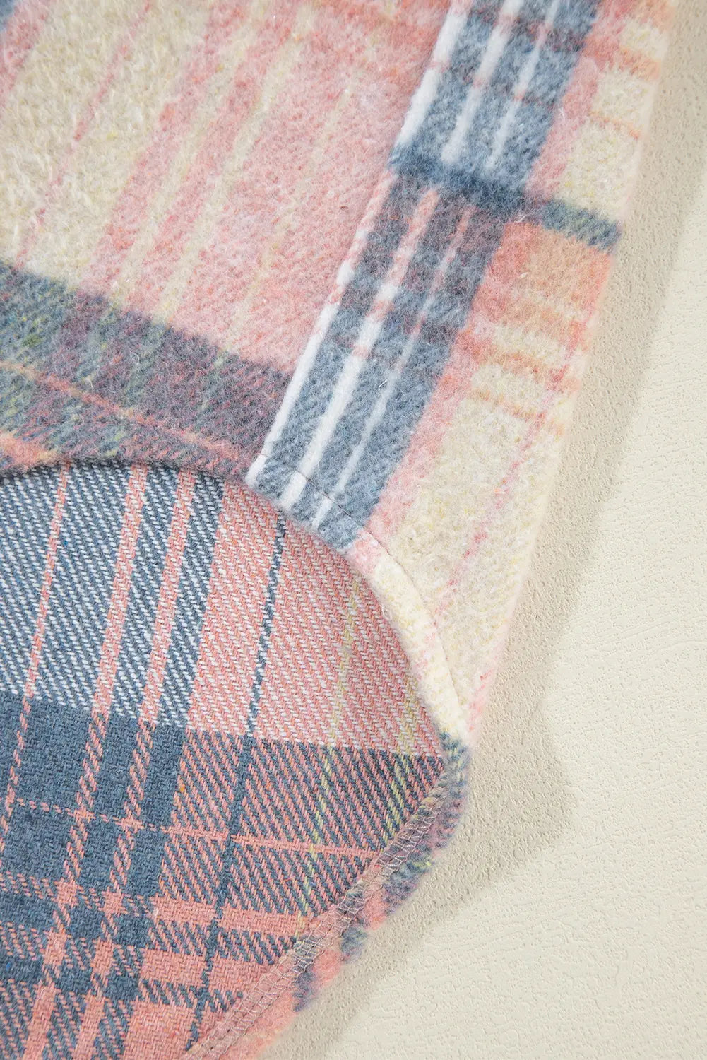 Close-up of a plaid fabric with pink and blue patterns on a neutral background