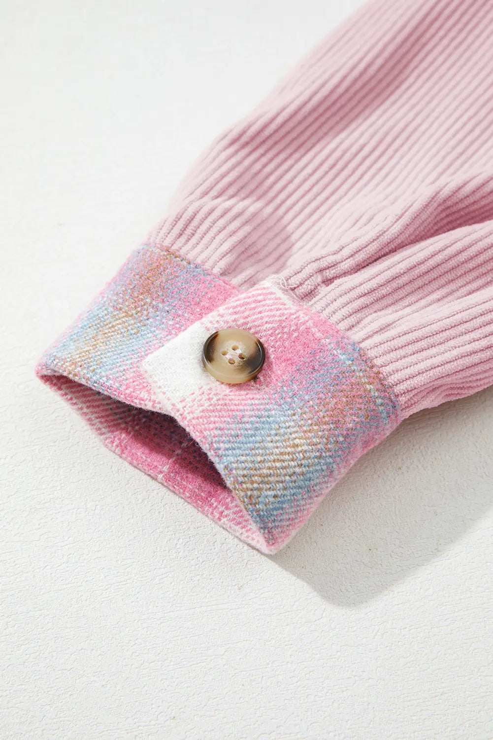 Close-up of a pink knitted sleeve with a button on a light background