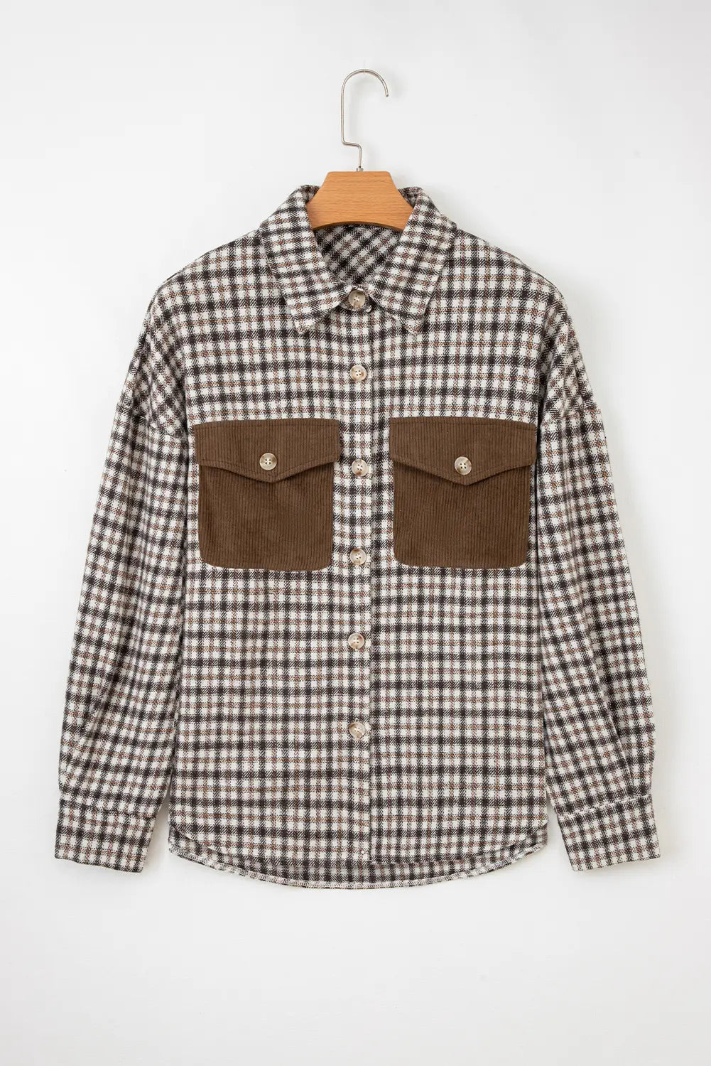 Plaid shirt with brown pocket flaps on a hanger against a white background