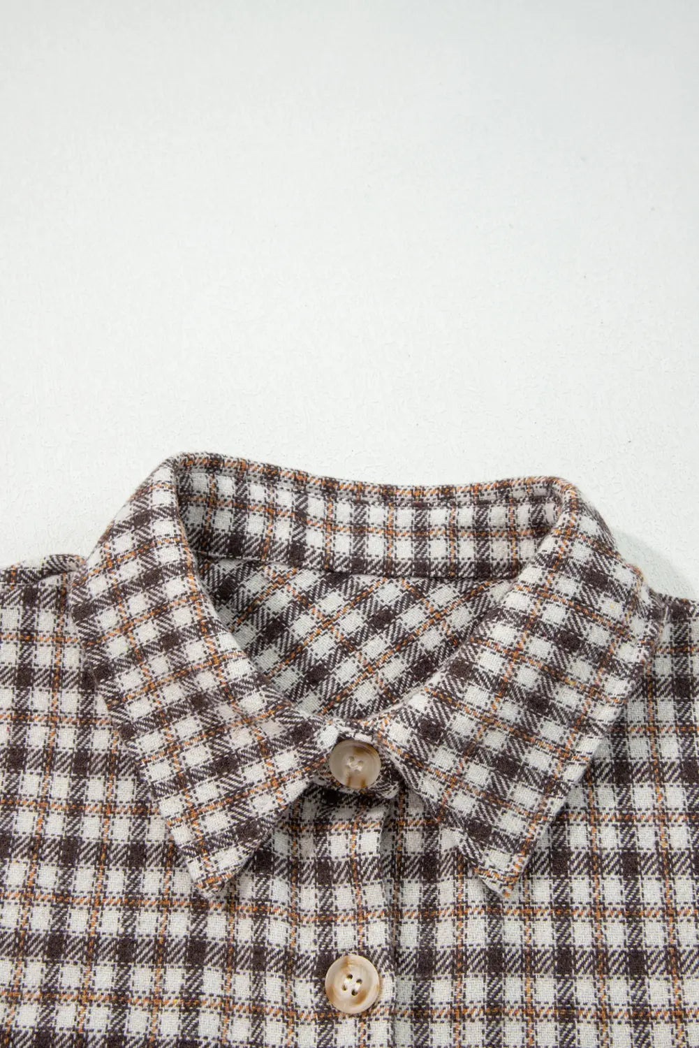 Close-up of a checkered shirt collar with buttons on a white background