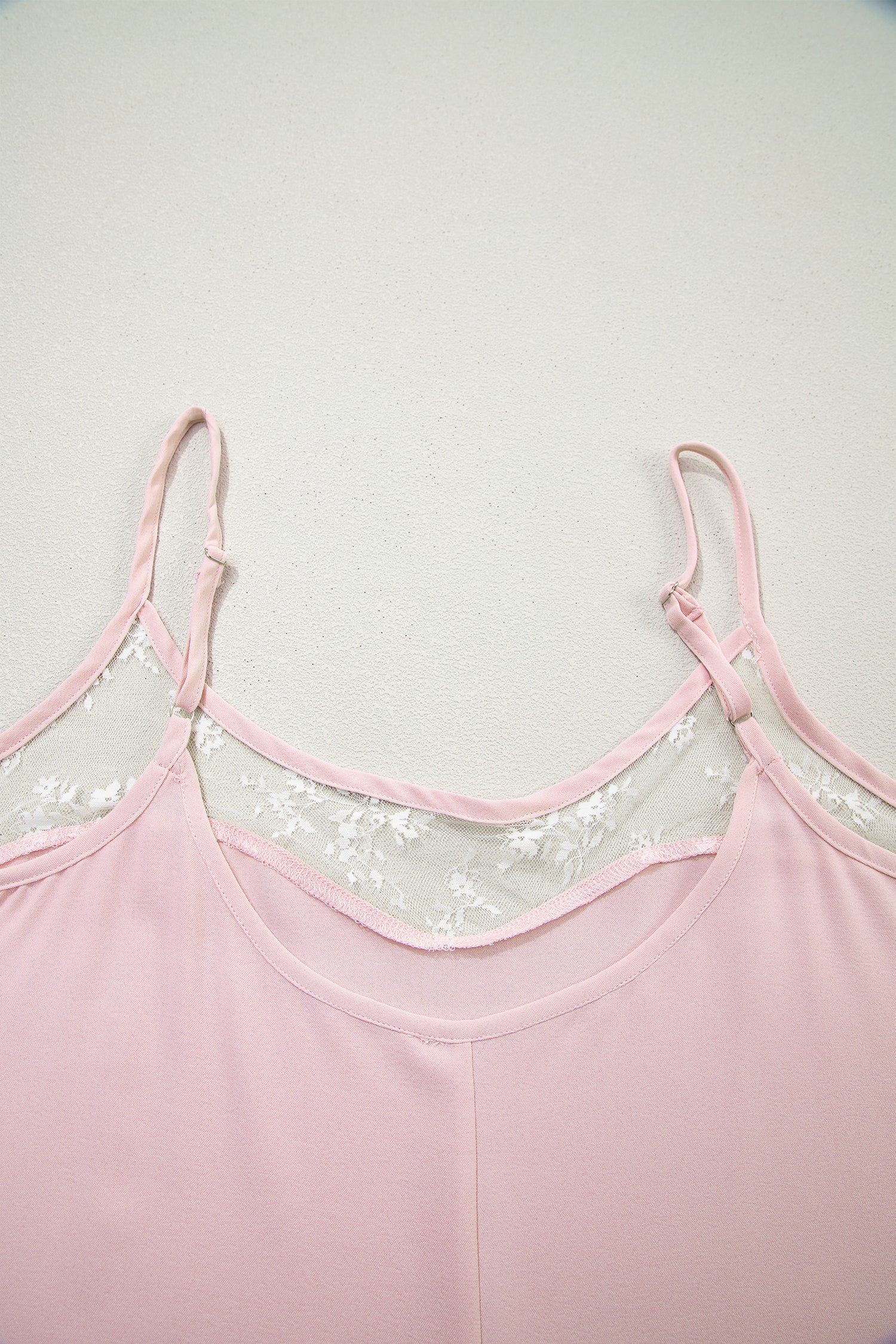 Pink top with lace detailing on a light gray background