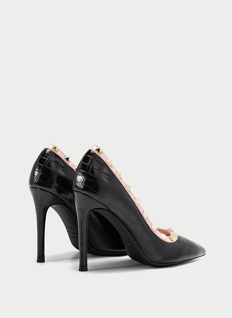 Black high-heeled shoes with decorative pink elements on a light gray background