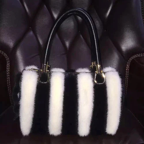 Black handbag with white fur tassels on a dark textured background