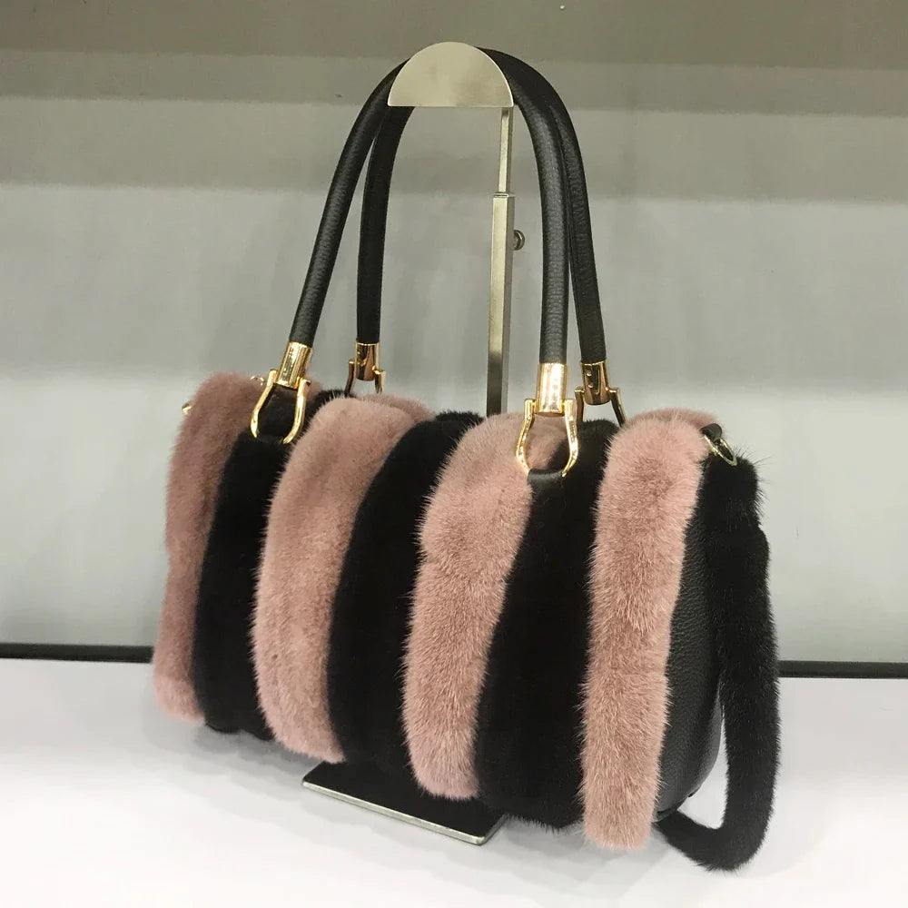 Black handbag with pink fur accents on a stand against a neutral background
