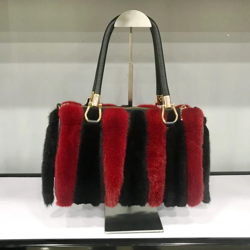 Handbag with red and black fur accents on a stand