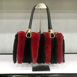 Handbag with red and black fur accents on a stand