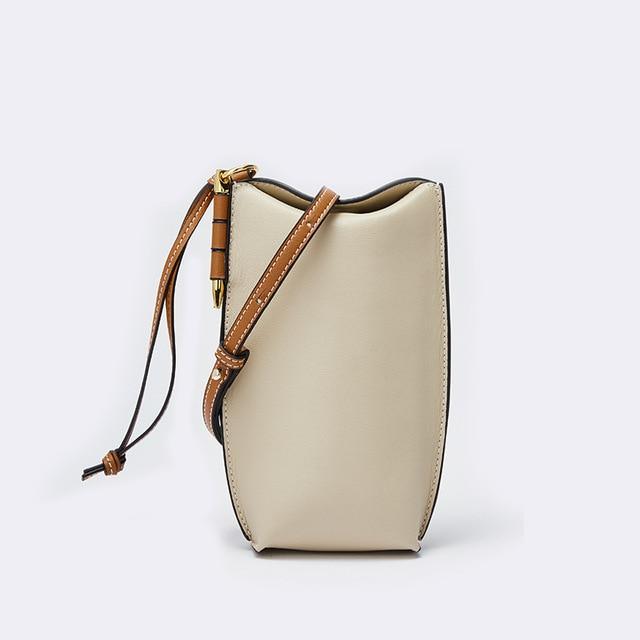 Beige handbag with brown strap on a white background