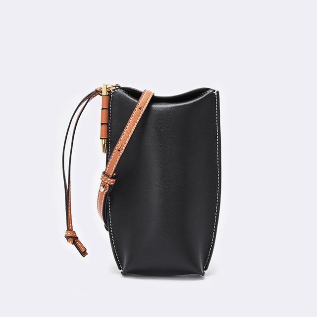 Black handbag with brown strap on a light gray background
