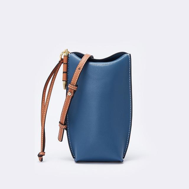 Blue handbag with brown strap on a light gray background