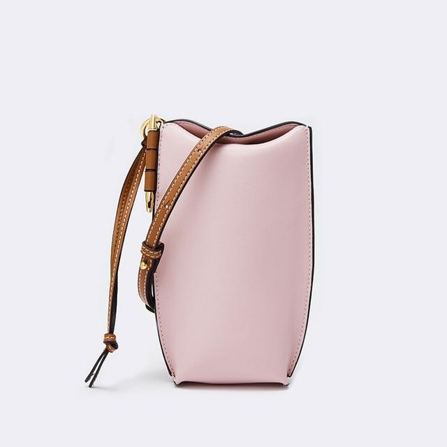 Pink handbag with brown strap on a light gray background