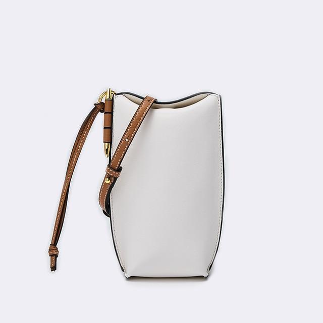 White handbag with brown strap on a light gray background